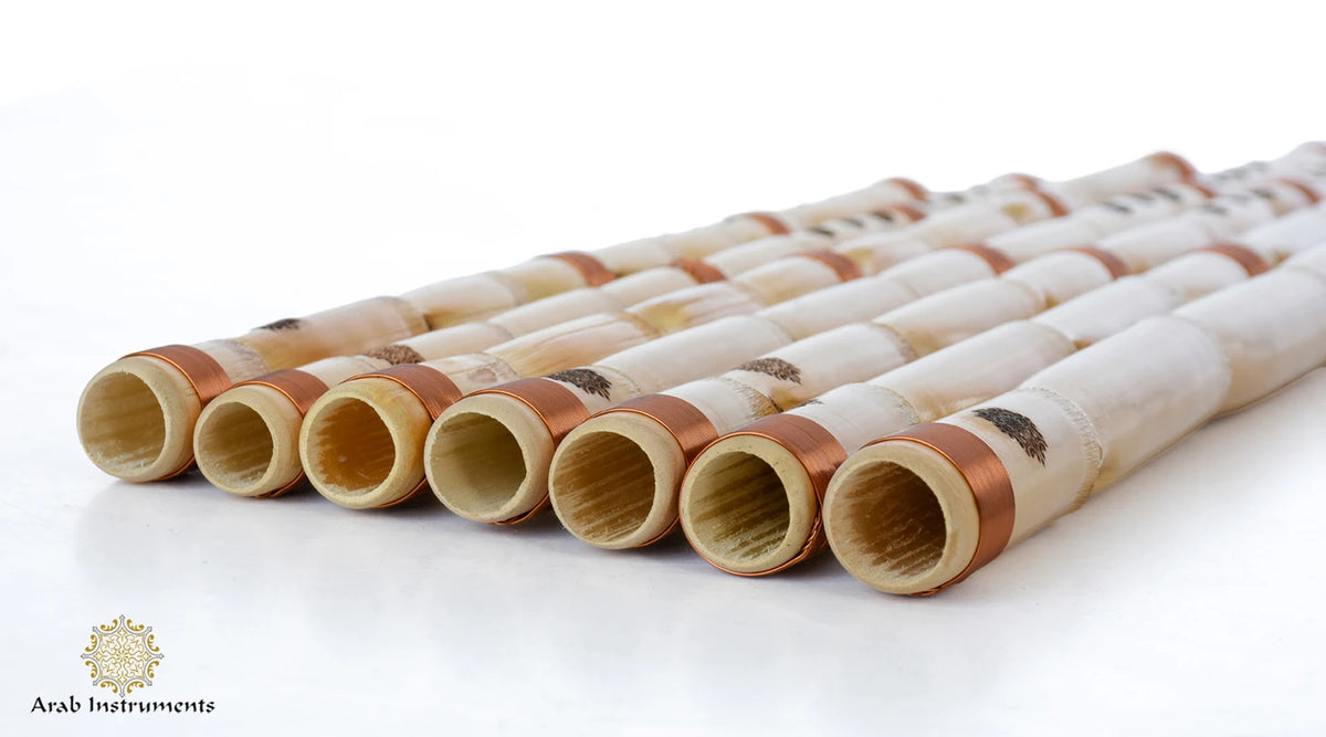 Close-up of seven Egyptian ney flute ends showing natural reed interiors, copper-colored bindings, and signature marks